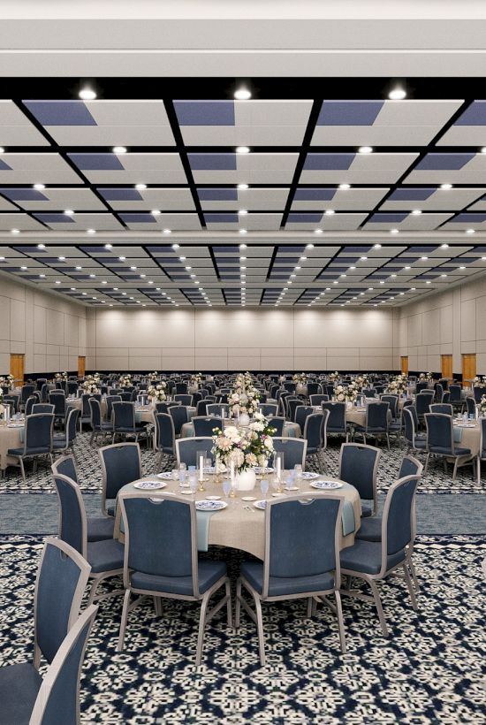 A large banquet hall with round tables set for a formal event, blue chairs, floral centerpieces, and a patterned carpet under bright ceiling lights.