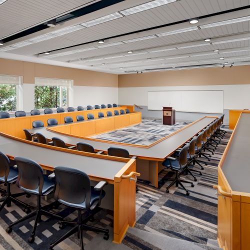 A classroom or lecture hall with rows of desks and chairs, a front whiteboard, and a modern setup for teaching.